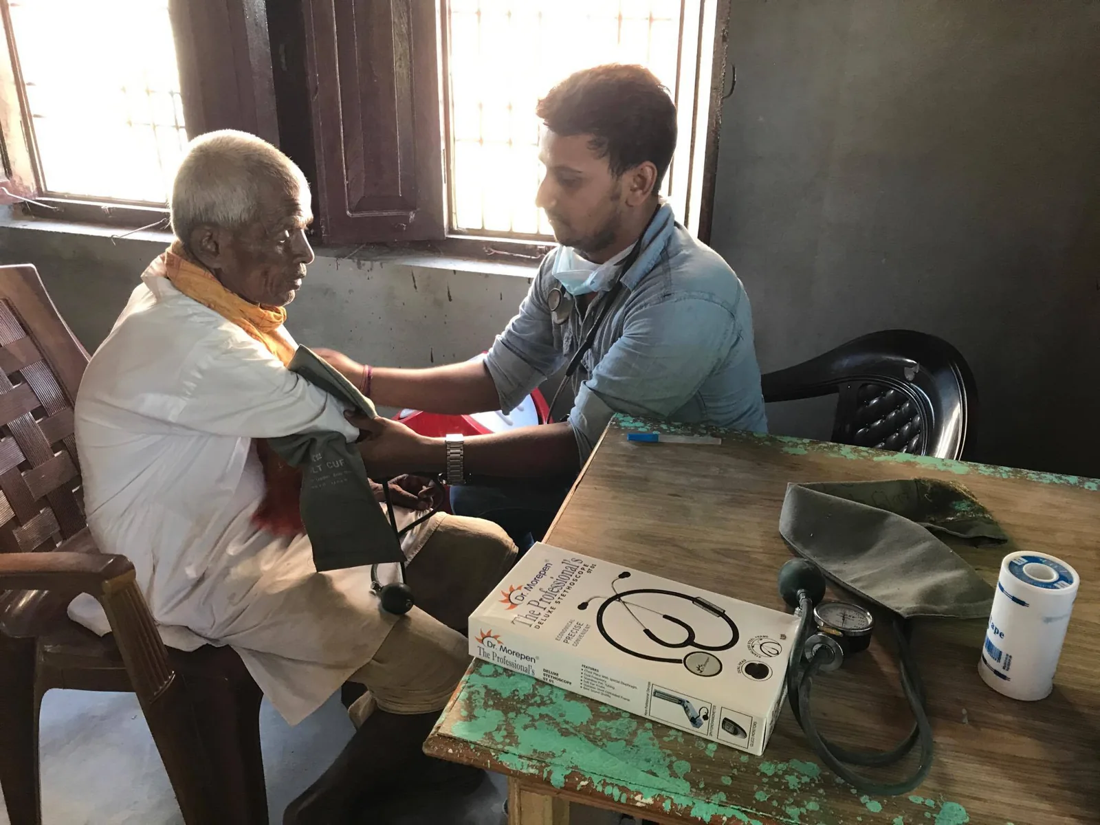 A health worker checks a patient’s blood pressure at a BGSK health camp